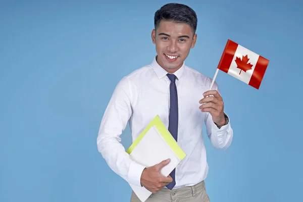 Kitap ve bayrak ile Asyalı genç yakışıklı öğrenci, açık mavi arka plan