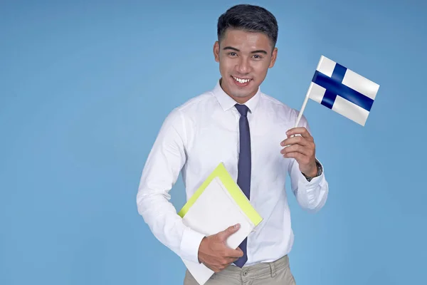 Asian young handsome student with book and flag, on light blue background — Stock Photo, Image