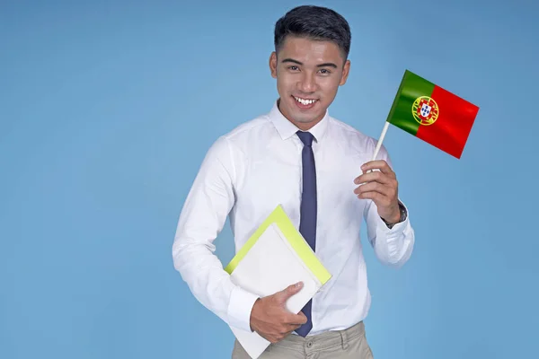 Asian young handsome student with book and flag, on light blue background — Stock Photo, Image