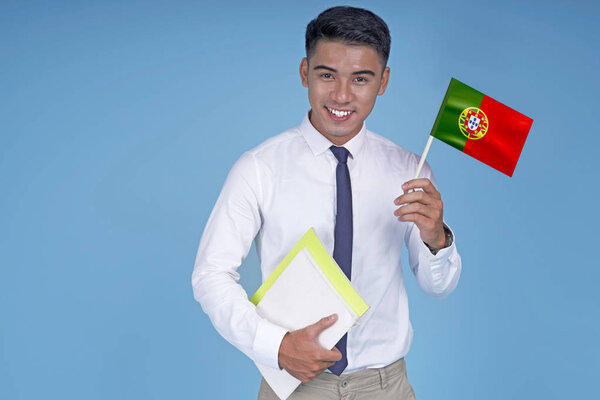 Asian young handsome student with book and flag, on light blue background