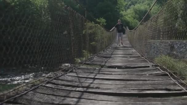 Man Crossing Old Hanging Wooden Bridge — Stock Video