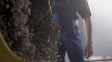 Adam iş giysisi içinde beton karıştırıcı el arabası dan yağıyor. 