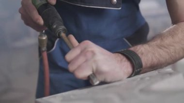 Adam iş giysisi içinde bir makine ile kaya oyma heykel..