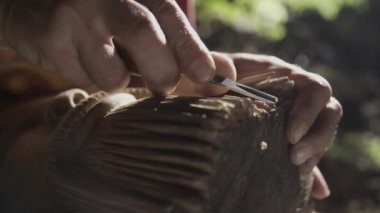 Yaşlı adam bir mağarada ahşap oyma.