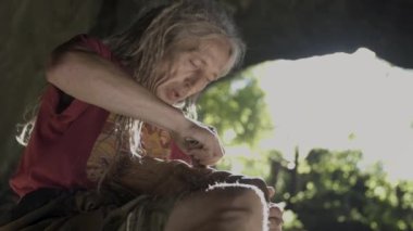 Yaşlı adam bir mağarada ahşap parlatma.