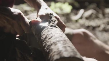 Yaşlı adam bir mağarada ahşap oyma. O bıçak kullanıyor. 