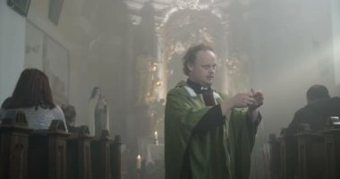 Sigara thurible ile yürüyen bir kilisede rahip
