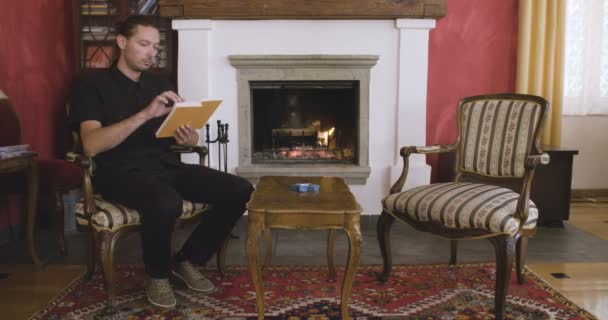 Hombre Leyendo Libro Delante Una Chimenea — Vídeos de Stock