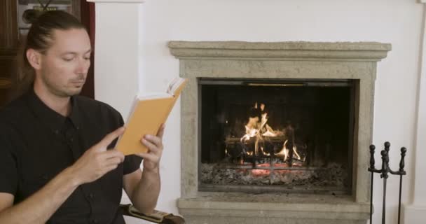 暖炉のそばで本を読んでいる人 — ストック動画