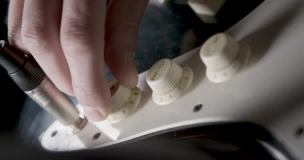 エレク トリック ギターのトーン ボリュームのノブを調整するギタリスト — ストック動画