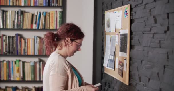 Mujer joven está arreglando pin board — Vídeo de stock