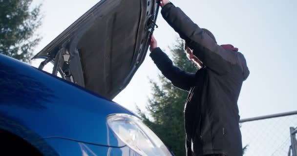 Мужчина сломал свою машину и проверяет под капотом на наличие проблем. — стоковое видео