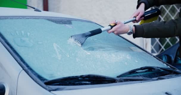 Homem com raspador raspando gelo da janela da frente do carro — Vídeo de Stock