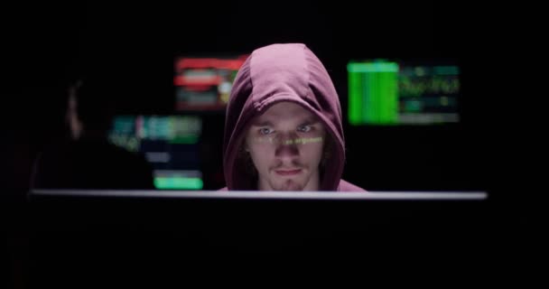 Hacker programmer working at the computer in a secret room filled with display screens — Stock Video