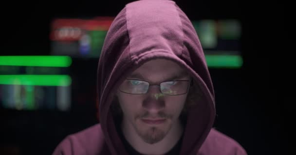 Hacker programming in a dark room with screens with data behind — Stock Video