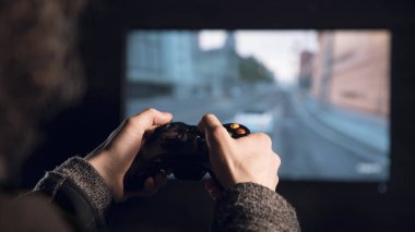 Bir gamepad tutan adam, ekranın önünde