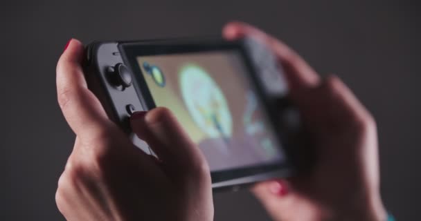 Menina com unhas vermelhas está jogando em um console de videogame portátil — Vídeo de Stock