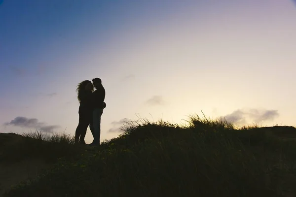 Enamored couple embraced at sunset in a backlit photo