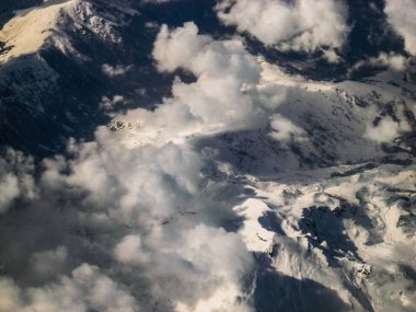 Bulutlar havadan görünümü arasında karlı dağlar