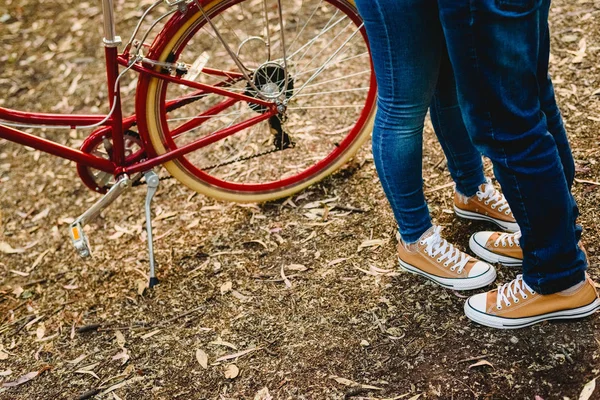 Couple of lovers with green sneakers and jeans standing next to a vintage bicycle