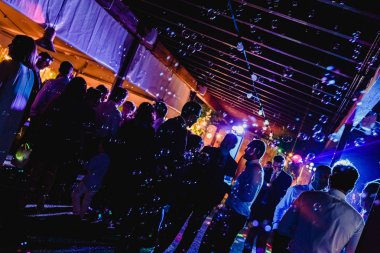 Arkadan aydınlatmalı gece parti ışıkları lazerler ve içme ve dans pistinde dans insanlar ile