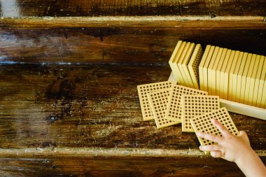 Montessori sınıfta ahşap arka plan üzerinde sayım küpleri manipüle çocuğun elleri