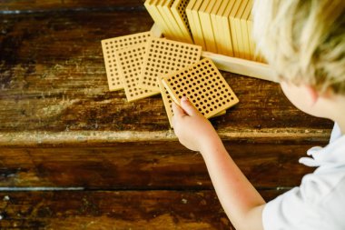 Montessori sınıfta ahşap arka plan üzerinde sayım küpleri manipüle çocuğun elleri