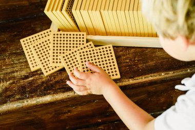 Montessori sınıfta ahşap arka plan üzerinde sayım küpleri manipüle çocuğun elleri