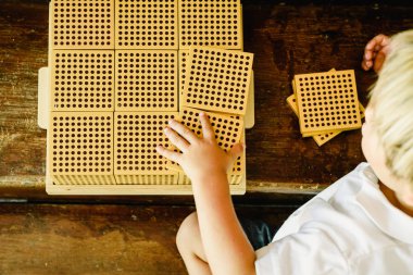 Montessori sınıfta ahşap arka plan üzerinde sayım küpleri manipüle çocuğun elleri
