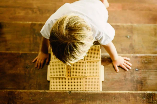 男孩的手在蒙台梭利教室的木质背景上操纵计数立方体 — 图库照片
