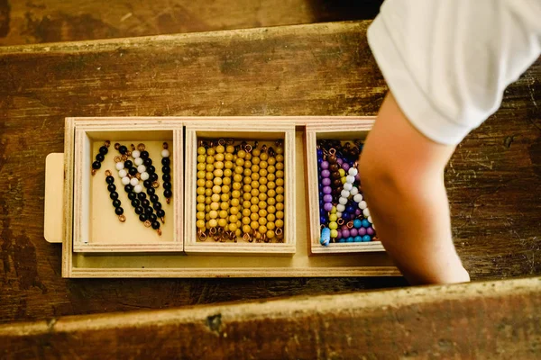 Hands of a child manipulating educational materials to learn to count in a Montessori classroom.