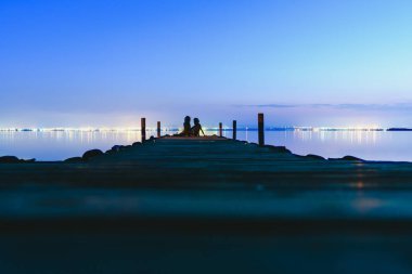 Günbatımında sakin su ile bir göl kenarında bir iskelede dinlenme insanlar rahat