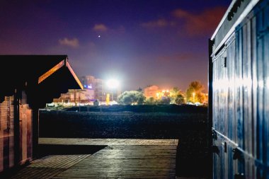 Bir yaz gecesinde bir plajda ahşap kulübeler.