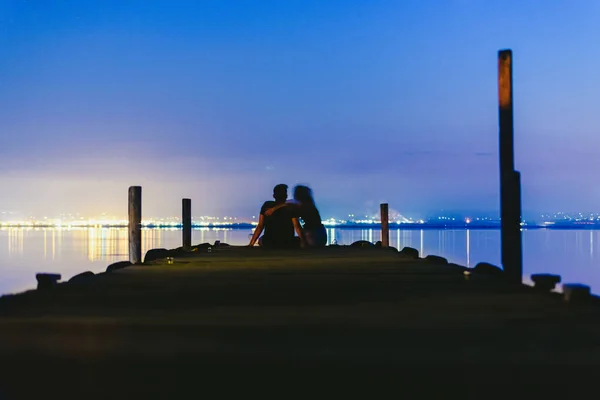 人们在夕阳下的一个码头上休息放松 平静的水 — 图库照片
