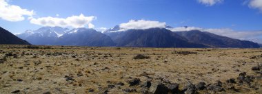 Bir kamyonet ve karavan gezisi sırasında dramatik gökyüzü ile Yeni Zelanda Alplerdeki karlı dağlık manzara.