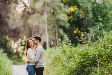 Aşık çift sarılma ve yeşil yolun ortasında gülüyor