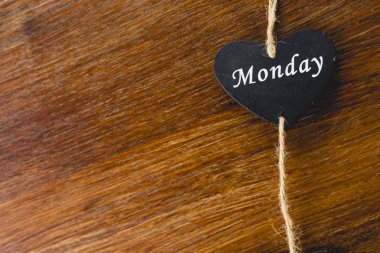 Siyah ahşap kalp üzerinde Pazartesi yazılı haftanın günü ile.