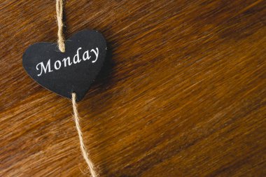 Siyah ahşap kalp üzerinde Pazartesi yazılı haftanın günü ile.