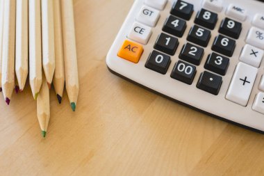 Renkli kalemler ve hesap makinesi bir tablo üzerinde.