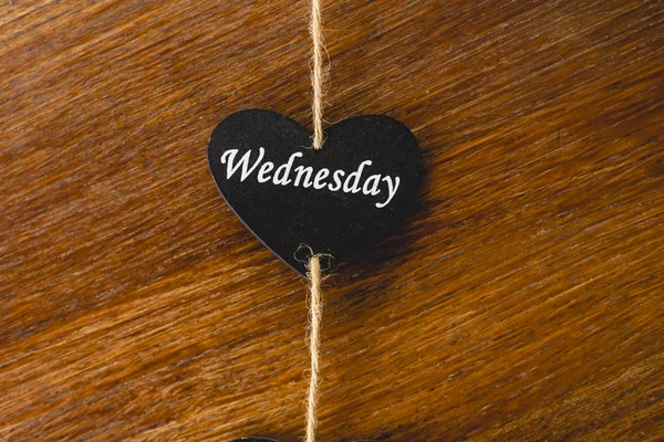 Heart of black wood with day of the week written on it, wednesday