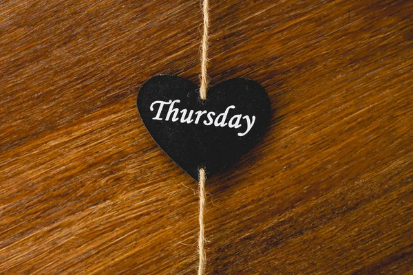 Black wooden heart with day of the week written on it, Thursday