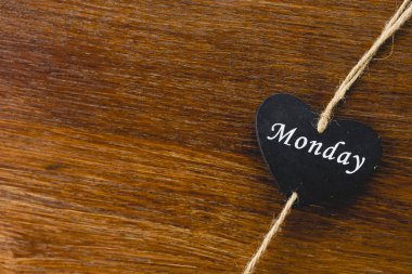 Siyah ahşap kalp üzerinde Pazartesi yazılı haftanın günü ile.