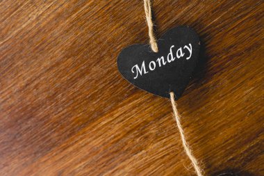 Siyah ahşap kalp üzerinde Pazartesi yazılı haftanın günü ile.