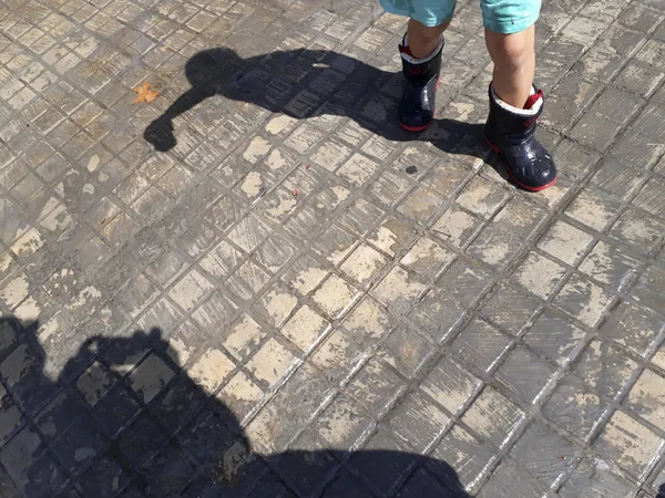 Happy child with wet rain boots on a rainy autumn day.