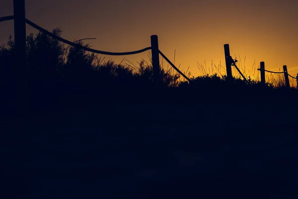 Warm sunset with silhouette of beach dunes