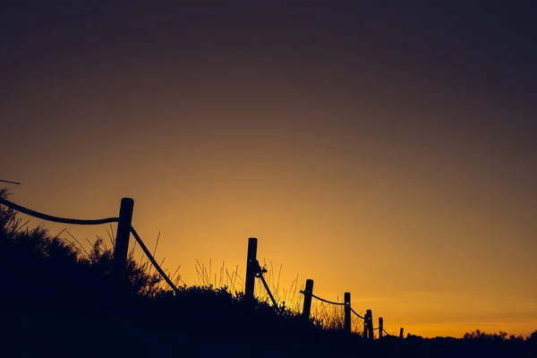 Warm sunset with silhouette of beach dunes