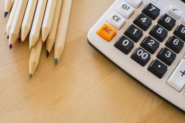 Renkli kalemler ve hesap makinesi bir tablo üzerinde.