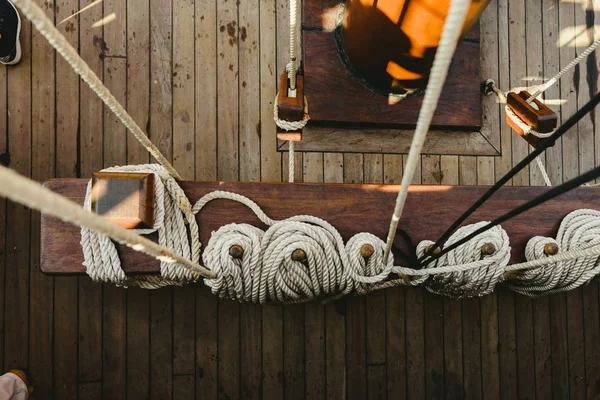 Ropes to hold the sails of an old sailboat rolled.