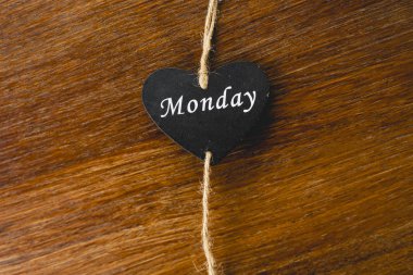 Siyah ahşap kalp üzerinde Pazartesi yazılı haftanın günü ile.