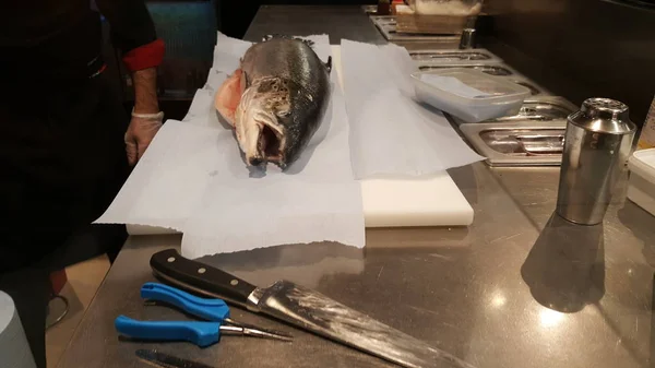 Man preparing a salmon to make sushi in a fish market.